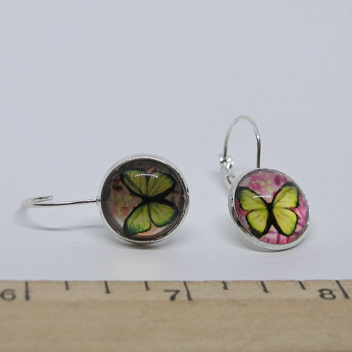 Butterfly-themed earrings on a white background with a ruler for scale.