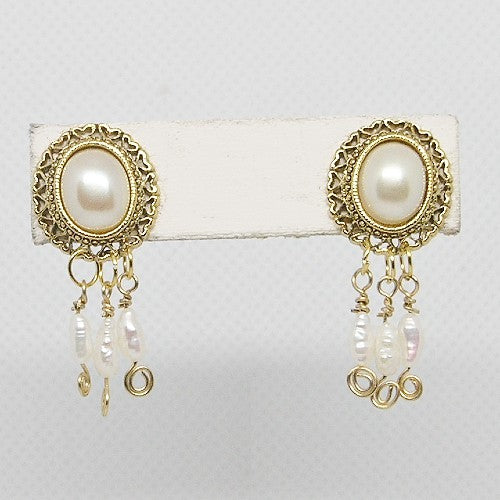 Gold-framed pearl earrings on a white card with a light gray background