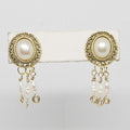 Gold-framed pearl earrings on a white card with a light gray background
