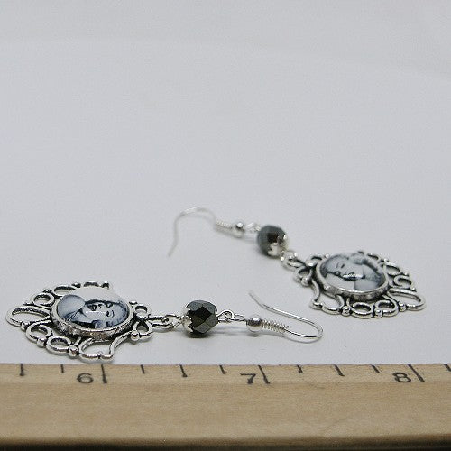 Silver earrings with black beads on a ruler for size reference