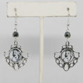 Pair of earrings with decorative frames and black beads on a white background