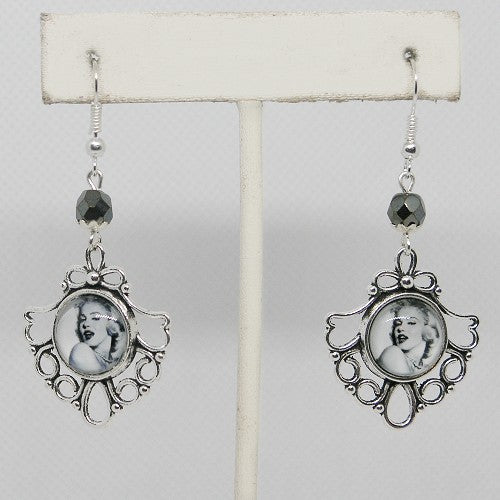 Pair of earrings with decorative frames and black beads on a white background