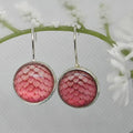 Pink patterned earrings on a white floral background