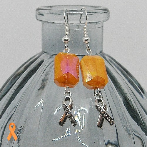 Orange beaded earrings with silver ribbon charms on a glass bottle.