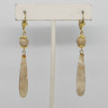 Pair of earrings with gold and beige beads on a white background