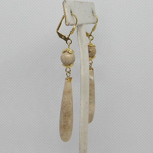 Pair of earrings with gold accents and stone beads on a gray background