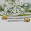 Silver hair pins with yellow circular ends on a white background with flowers.
