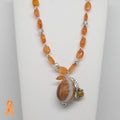 Necklace with orange beads and a large central bead on a white background