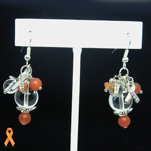 Pair of earrings with quartz balls and orange beads on a white stand against a black background.