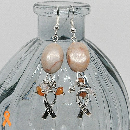 Peach colored stone earrings with 'hope' charms on a glass bottle