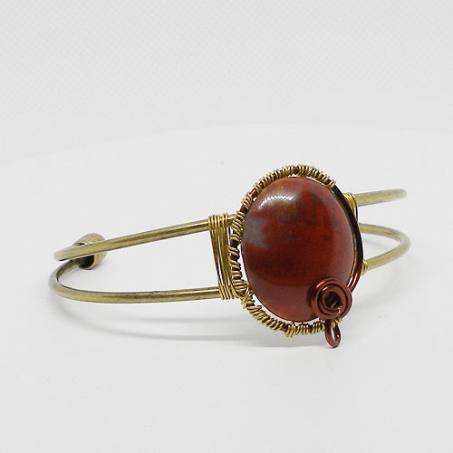 Brass bracelet with a red stone on a white background