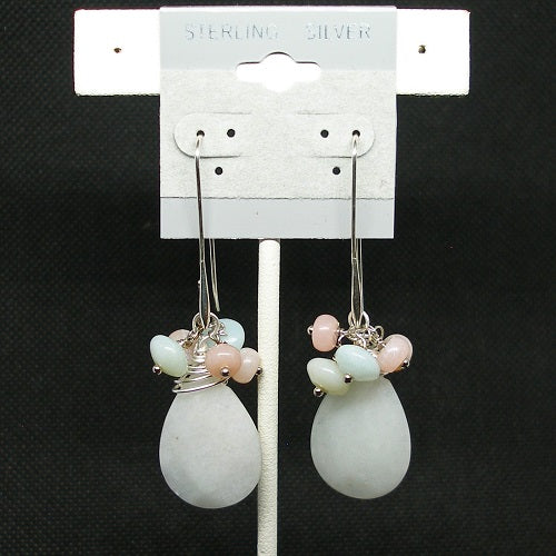 Pair of earrings with teardrop-shaped stones on a white card against a black background