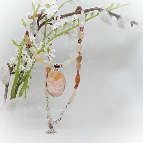 Necklace with a large peach colored stone pendant on a branch with white flowers