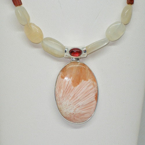 Necklace with a large peach colored stone pendant and smaller beads on a white background