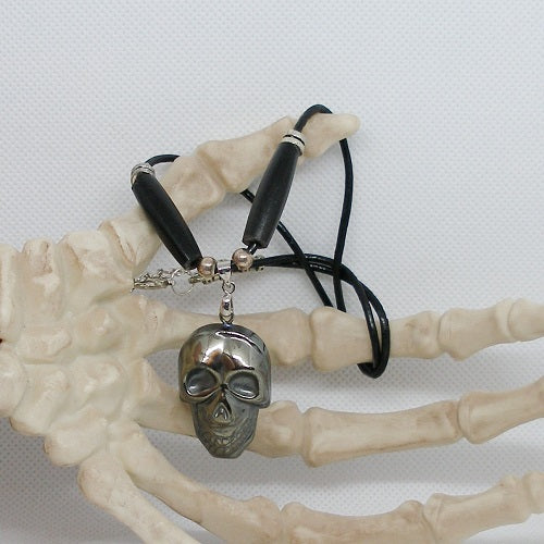 Skull pendant necklace on a skeleton hand with a white background