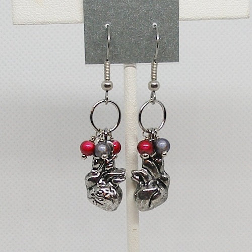 Pair of silver heart earrings with red and grey beads on a gray background