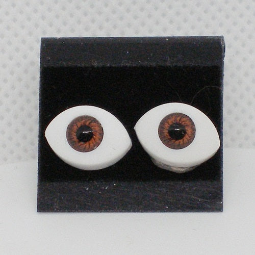 Pair of plastic eyes with brown pupils on a black display stand against a gray background