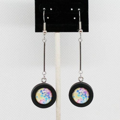 Earrings with colorful circular charms on a black card against a white background