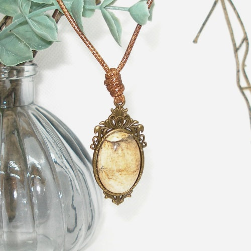 Necklace with a pendant featuring a stone, placed against a white background.