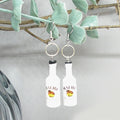 Bottle-shaped earrings hanging from a branch.