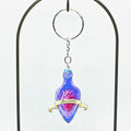 Decorative keychain with a purple bottle and heart design on a white background