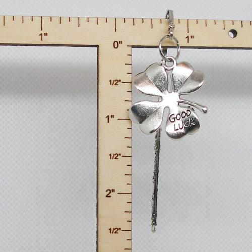 Silver four-leaf clover bookmark with 'Good Luck' on a ruler for scale.