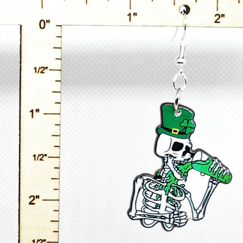 Skeleton wearing a green hat with a shamrock design, holding a green beer mug, on a white background with a ruler for scale.