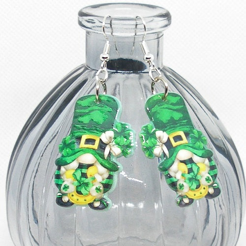 Green gnome earrings with shamrock details on a clear glass bottle.