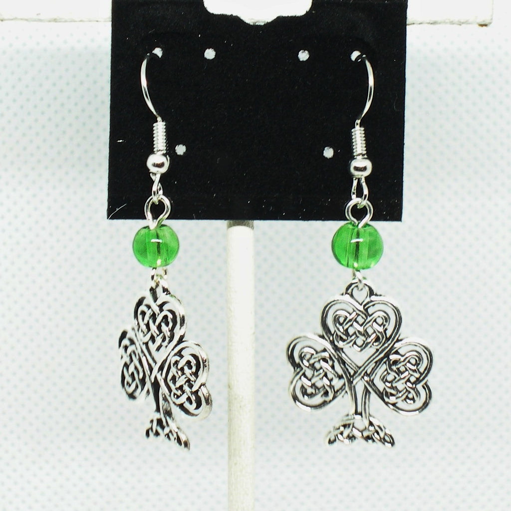 Pair of silver shamrock earrings with green beads on a display card.