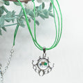 Necklace with a pendant featuring a shamrock design and text, against a light background with green leaves.