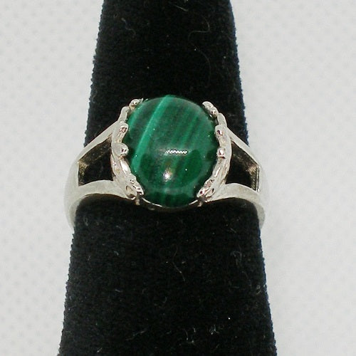 Silver ring with a green stone on a black stand against a white background