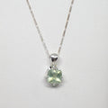 Silver necklace with a green gemstone pendant on a white background