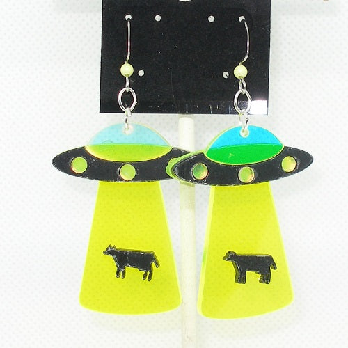 Alien spaceship earrings with cow designs on a white background
