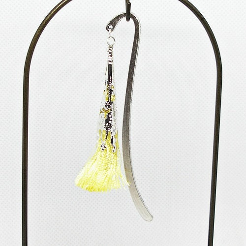 Metal bookmark with a yellow tassel on a white background