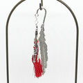 Feather shaped metal bookmark with red tassel on a white background