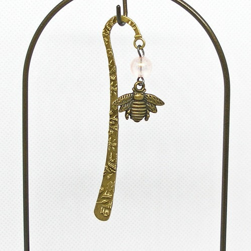 Brass bookmark with bee charm on a white background