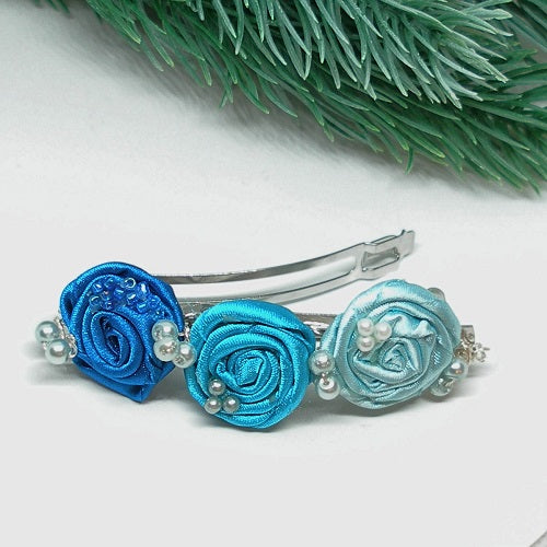 Decorative hair clips with blue and turquoise flowers on a white background