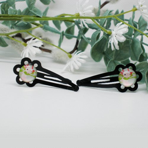 Black hair clips with axolotl designs on a white background