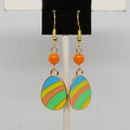 Colorful striped earrings with orange beads on a gray background