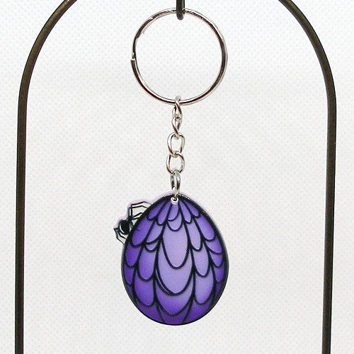 Keychain with purple and black goth egg with spider and web design on a white background