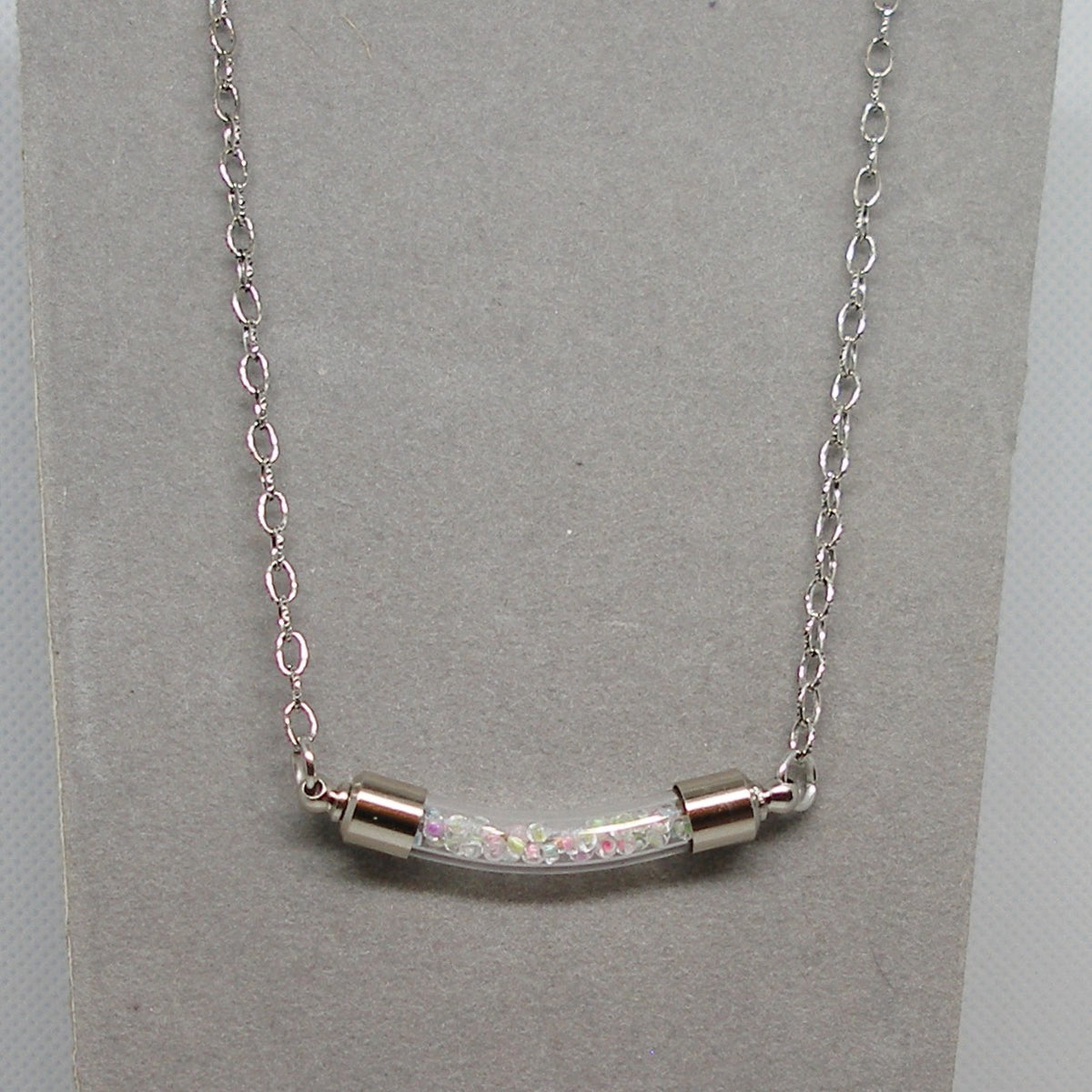 Silver necklace with a bar pendant on a gray card
