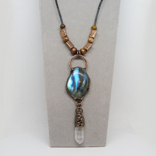 Necklace with a pendant featuring a blue stone and clear crystal on a gray card.