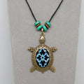 Necklace with a turtle pendant featuring a blue cabochon on a gray background