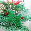 Green glittery Christmas tree earrings with red ornament on a branch.