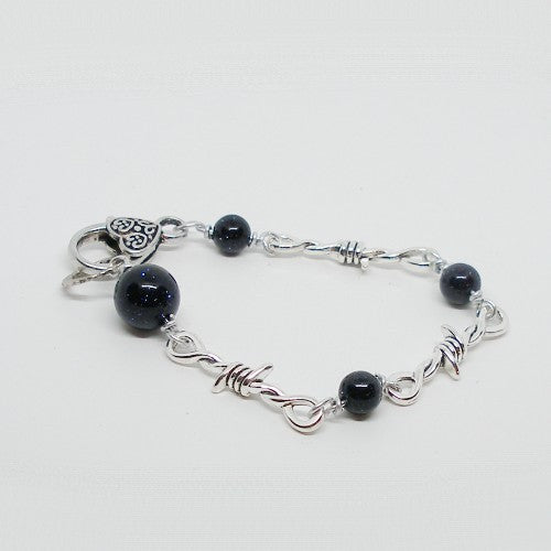 Silver bracelet with dark color beads on a white background